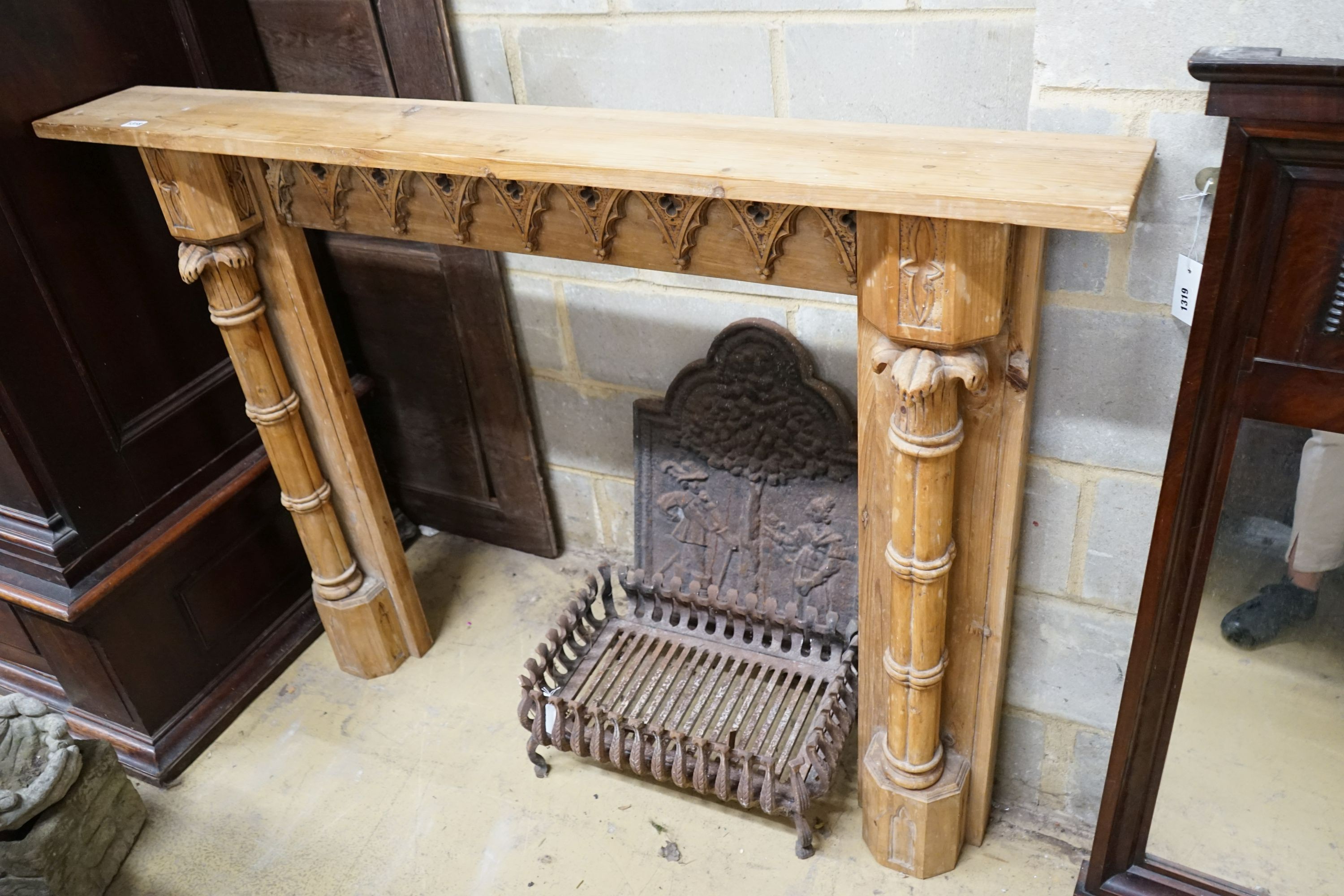 A George III style limewood chimneypiece, in the Strawberry Hill Gothic style, width 150cm, height 111cm together with a cast iron fireback and fire basket (3)